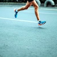 Ein Läufer mit blauen Laufschuhen auf dem Asphalt