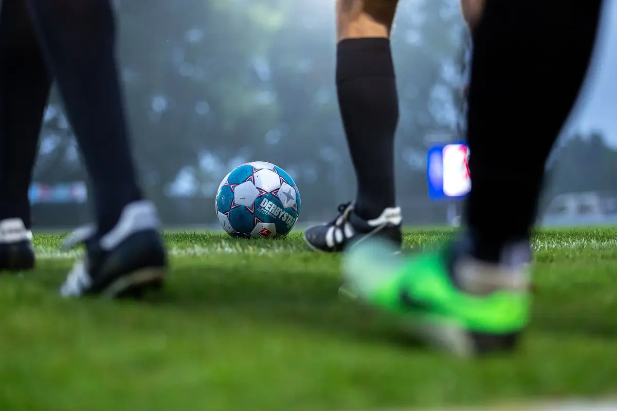 Ein Fußball und einige Füße auf dem Rasen