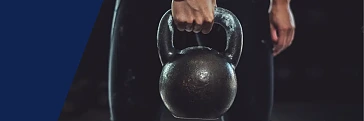 Eine Frau hebt Kettlebells in die Höhe