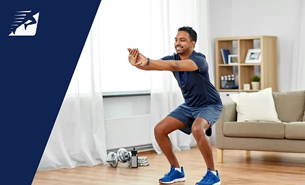 Ein Mann mit Sportschuhen bei Kniebeugen im Wohnzimmer